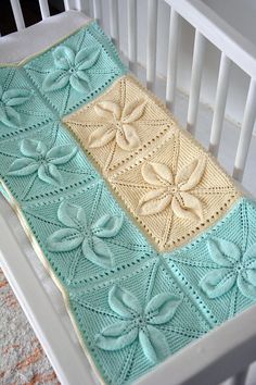 a crocheted blanket on top of a white crib next to a baby's bed