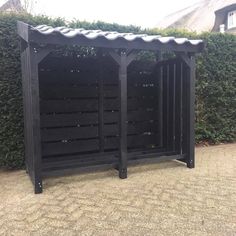 a black wooden structure sitting in front of a hedge