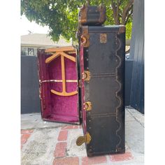 an open trunk sitting on top of a sidewalk next to a pink velvet covered box