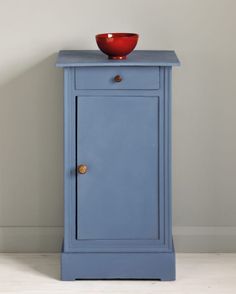 a blue cabinet with a red bowl on top