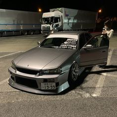 a silver car parked in a parking lot next to a truck