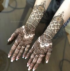 two hands with henna tattoos on them, one is showing off the intricate design