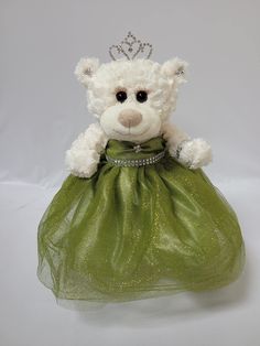 a white teddy bear wearing a green dress with a tiara on it's head