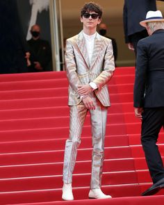 a man standing on top of a red carpet next to another man in a suit