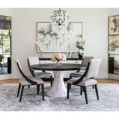 a dining room table with chairs and a chandelier hanging from the ceiling above it