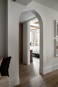 an archway leads into a bedroom with a bed in the background and wood floors on either side