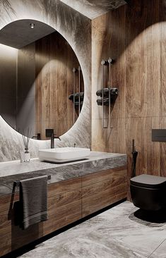 a modern bathroom with marble counter tops and wooden cabinets, along with a round mirror on the wall