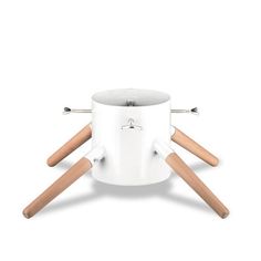 a white cup with wooden spoons and handles on it's legs, sitting on top of a table