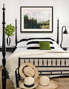 a bedroom with black and white bedding, green pillows and hats on the floor