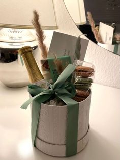 an open gift box filled with cookies and wine bottle sitting on a desk next to a mirror