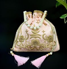 Grab our Exclusive Blush Pink Designer Zardosi Work Potli Bag With Drawstring Pattern and Tassels  Made by Indian Women Artisans Made up of premium material This potli, which combines traditional and modern embroidery work, looks great with both Indian and Western attire. It is perfect for weddings and festive occasions. It would be the perfect complement to your designer saree, lehanga, or any type of dress.  It can hold all of your essentials and accessories, making it a great gift for any woman. Drawstring Pattern  Compartment : 1 compartment Spacious Color : Blush Pink  Pearl Cord Dimensions : 9.5" X 9.5" Disclaimer :  Product color may slightly vary due to photogenic effect. Indian Wedding Giveaways, Embroidered Handbag, Potli Bags, Bag Elegant, Handcrafted Bags, Velvet Choker, Modern Embroidery, Pine Needles, Pink Pearl