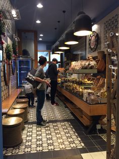 two women are standing in front of a bakery counter with breads and pastries