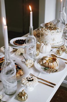 a white table topped with lots of food and candles