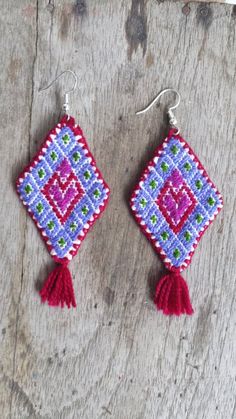 the earrings are decorated with beads and tassels on wooden background, closeup