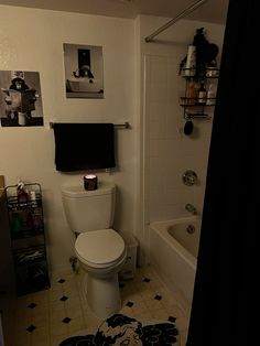 a white toilet sitting in a bathroom next to a bath tub and shower curtain with pictures on the wall above it