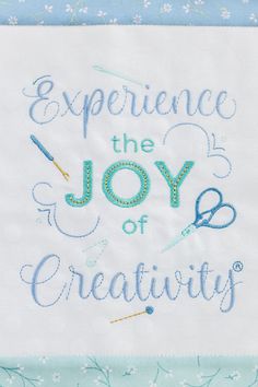 the words experience the joy of creativity are embroidered onto a white piece of paper with blue thread