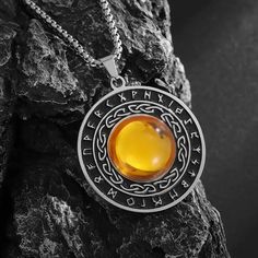 a necklace with an orange stone in the center on top of a rock next to a black background