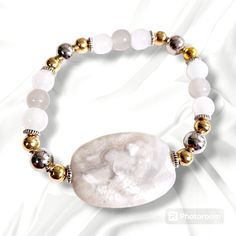 Beautiful white agate stone surrounded by silver and gold metal beads with clear white and gray glass beads. This stretch bracelet is 7-inches Adjustable White Agate Stretch Bracelet, White Adjustable Agate Stretch Bracelet, White Agate Spiritual Stretch Bracelet, Silver Agate Stretch Bracelet With Natural Stones, White Agate Beaded Bracelets With Natural Stones, Silver Agate Stretch Bracelet, White Beaded Agate Bracelets, White Agate Beaded Bracelets For Spiritual Use, White Stretch Bracelet With Silver Beads