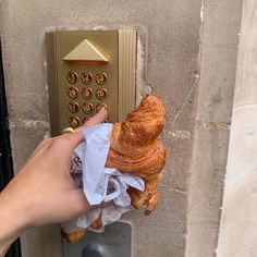 a person holding onto a croissant in front of a hotel keypad on a wall