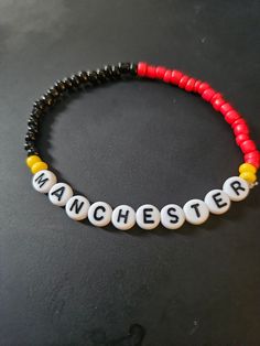 Manchester United Soccer Beeded Bracelet.  Soccer themed Avaliable in multiple colors, size. Adjustable Beaded Bracelets With Letter Beads As Souvenir, Adjustable Themed Bracelets With Letter Beads, Customized Themed Bracelets, Black Novelty Bracelets With Round Beads, Novelty Letter Beads Wristband Bracelet, Black Round Beads Novelty Bracelet, White Themed Beaded Bracelet, Customized Themed Beaded Bracelets, Customized Red Beaded Bracelets With Round Beads