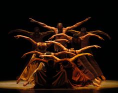 a group of people standing on top of each other in front of a black background