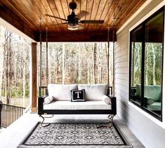 a porch with a swing bed, rug and ceiling fan on the front porch area