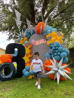 a young boy standing in front of a giant balloon art sculpture with an 8 on it's side