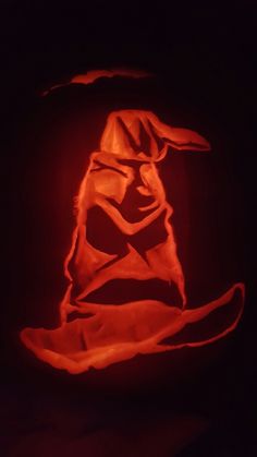 a carved pumpkin in the shape of a wizard's hat on a black background