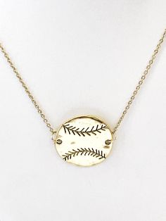 a necklace with a baseball on it and a gold disc in the shape of a leaf