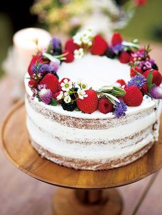 a white cake with strawberries and flowers on top