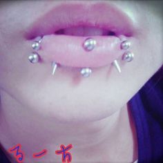 a woman with piercings on her tongue has four balls attached to her lip and is looking at the camera