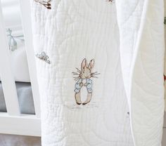 a white crib with an embroidered bunny on it