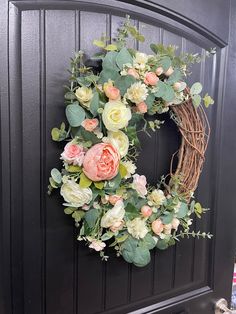 a wreath with flowers hanging on the front door