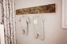 two baby ones are hanging on the wall next to a coat rack with hooks and clothes