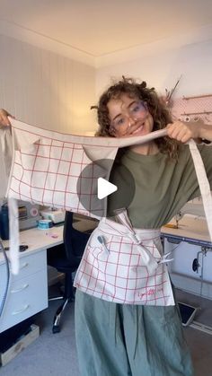 a woman in an apron is holding up a piece of fabric with scissors on it