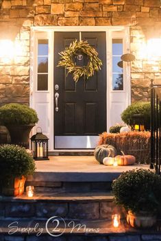 a front porch decorated for fall with pumpkins, candles and wreath on the steps