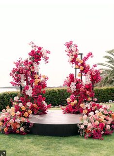 an outdoor ceremony setup with flowers and greenery on the lawn by the ocean in front of it