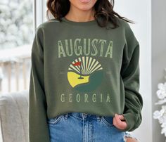 HOLIDAY ORDER DEADLINES TO ENSURE DELIVERY BY XMAS- USA- DEC 12 2023 CANADA- NOV 28 2023 EUROPE- CAN'T GUARANTEE ARRIVAL BY XMAS Fore! Calling all golf lovers - get ready to tee off in style with our Augusta Georgia Golf Sweatshirt! This cozy sweatshirt features a distressed serif font and a circle graphic representation of a golf course in the iconic Masters colors. The design is sure to score a hole-in-one with its vintage vibe and eye-catching visuals. Made from quality materials, this sweatshirt is perfect for hitting the links or chilling at the clubhouse. So, swing into action and add this Augusta Georgia Golf Sweatshirt to your collection today! Care Instructions - Wash in warm water, max 40C or 105F. - Use non-chlorine bleach only when necessary. - Do not dry clean. - Do not iron. Golf Sweatshirt, Golf Lover Gifts, Circle Graphic, Augusta Georgia, Club Sweatshirts, Golf Lover, Hole In One, Vintage Vibe, Cozy Sweatshirts