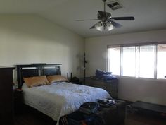 a bed sitting in a bedroom next to a window with two fan's on top of it