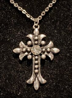 Necklace is silver in color Measures 18, 20 or 24 inches in length Pendant measures 1.5 inches in length and 1 inch in width Silver Adjustable Rhinestone Costume Necklace, Adjustable Silver Rhinestone Costume Necklace, Metal Cross Pendant Necklace With Rhinestones, Metal Rhinestone Cross Pendant Necklace, Silver Crystal Cross Pendant Necklace, Adjustable Silver Metal Rhinestone Necklace, Adjustable Silver Rhinestone Necklace With Bling, Adjustable Silver Necklace With Rhinestones, Silver Cross Jewelry With Rhinestones