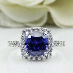 a blue and white diamond ring sitting on top of a table next to a flower