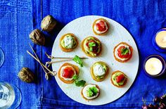 small appetizers are arranged on a white plate next to wine glasses and candles