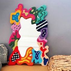 a colorful mirror sitting on top of a table next to a basket filled with rocks