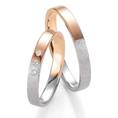 two gold wedding rings with diamonds on each side and one diamond in the middle, against a white background