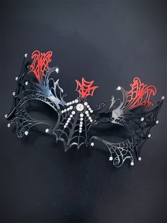 This mask boasts a mesmerizing combination of black and rich red, evoking an air of dark sophistication. Laser-cut metal forms an intricate spiderweb, symbolizing your power and mystique.  Shimmering rhinestones add a touch of opulence and mystery to your mask, ensuring you stand out in the shadows.


Age Group/Gender - Adult/Women

Size/Type - One size fits all adults

Mask Color - Red/Black

Mask Material - Laser cut metal

Accent Material - Paint Elegant Black Theater Masks, Black Gothic Mask For Festivals, Black Punk-style Masquerade Mask For Halloween, Black Gothic Fitted Masquerade Mask, Black Gothic Eye Mask For Masquerade, Masquerade Mask Black, Masquerade Mask Women, Black Masquerade, Spider Web Pattern