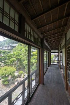 a long wooden walkway with lots of windows on each side and trees in the background