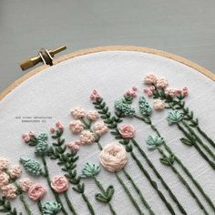 a close up of a embroidery on a hoop with pink and green flowers in it