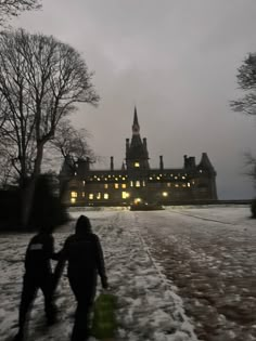 two people walking in the snow towards a large building