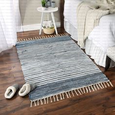 a white bed sitting next to a rug on top of a hard wood floor in a bedroom