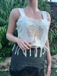 Introducing our Tree Of Life Tassel Top. This beautifully crafted crop top features a traditional Tree of Life motif, meticulously hand block printed on soft, breathable cotton. The intricate design is complemented by playful tassels, adding a touch of bohemian charm. The top has unstitched edges to make it look more natural and rugged. Perfect for warm weather, this top pairs effortlessly with high-waisted jeans, skirts, or shorts for a relaxed yet stylish look. Whether you're heading to a fest Summer Crop Top With Frayed Hem, Summer Cropped Top With Frayed Hem, Summer Cropped Crop Top With Frayed Hem, Spring Fringe Crop Top, Beach Embroidered Cotton Crop Top, Bohemian Cotton Tops With Frayed Hem, Bohemian Summer Tops With Frayed Hem, Bohemian Hand Printed Cotton Tops, Hand Printed Cotton Tops